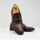 A pair of premium brown leather loafers with an antique gold horsebit and supportive medicated sole.
