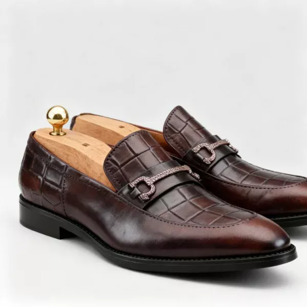 A pair of premium brown leather loafers with an antique gold horsebit and supportive medicated sole.